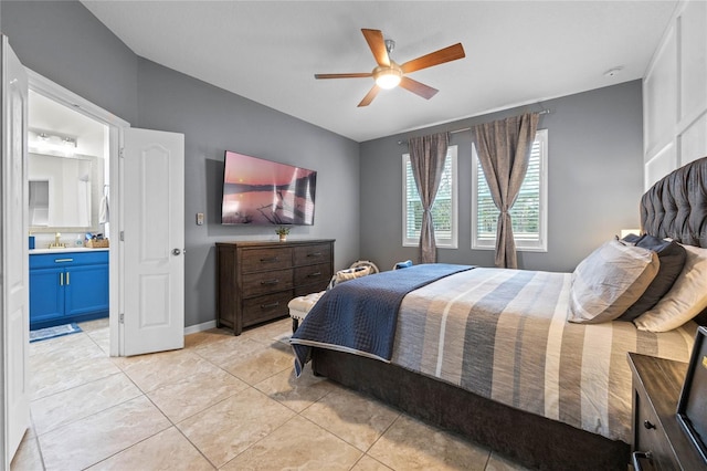 bedroom with ceiling fan, light tile patterned floors, sink, and ensuite bath