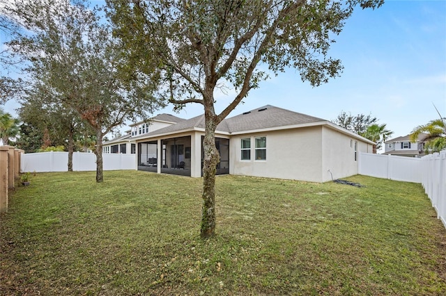 rear view of property featuring a sunroom and a lawn