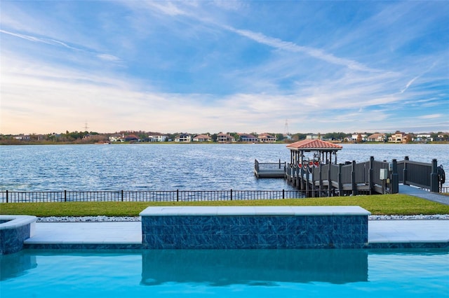 view of swimming pool with a lawn, a water view, and a dock