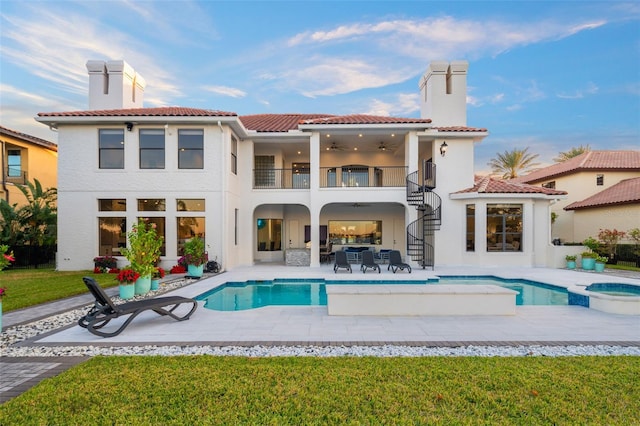 back of property with a pool with hot tub, a yard, a patio area, and a balcony