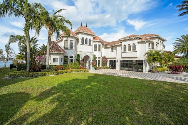 mediterranean / spanish-style home featuring a garage and a front yard