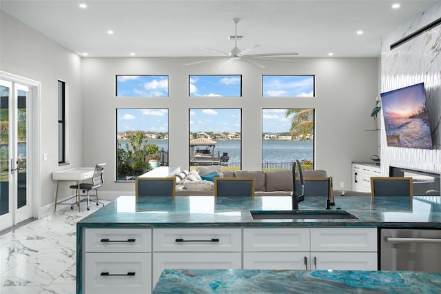 kitchen with white cabinetry, ceiling fan, dark stone counters, and sink