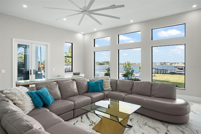 living room featuring ceiling fan, a healthy amount of sunlight, and a water view