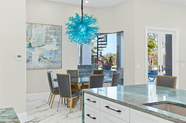 kitchen featuring white cabinetry, pendant lighting, an inviting chandelier, and dark stone counters