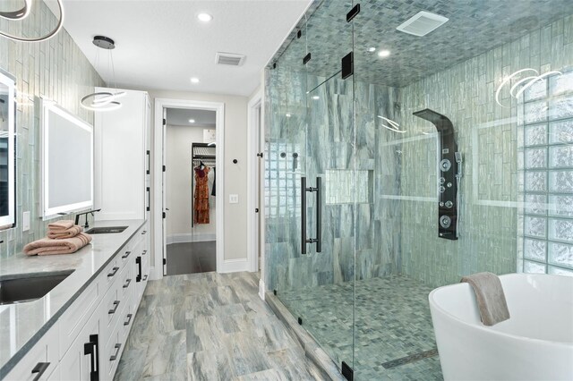 bathroom featuring hardwood / wood-style flooring, plus walk in shower, and vanity