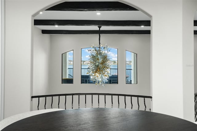 unfurnished dining area featuring beam ceiling and a chandelier