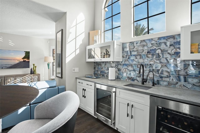 bar with white cabinetry, sink, and beverage cooler