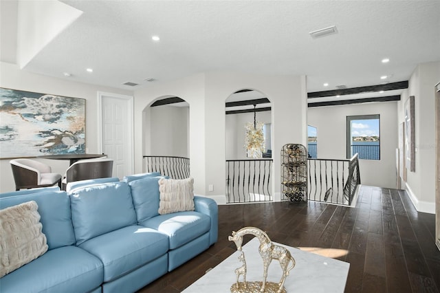 living room featuring beamed ceiling, dark hardwood / wood-style flooring, and a textured ceiling