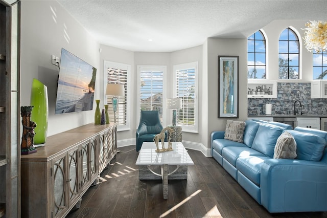 living room featuring dark wood-type flooring, a healthy amount of sunlight, and a textured ceiling