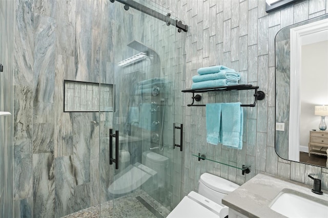 bathroom featuring walk in shower, vanity, toilet, and tile walls