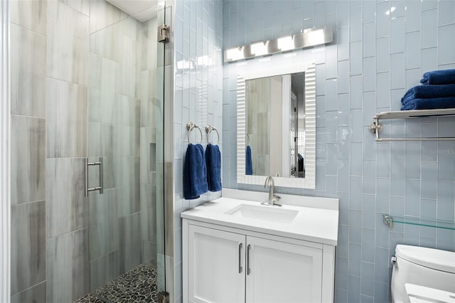 bathroom with tile walls, an enclosed shower, vanity, and toilet