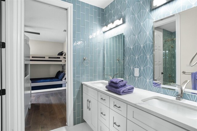 bathroom with hardwood / wood-style floors, vanity, a shower, and tile walls