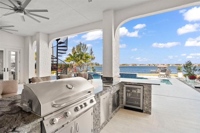 view of patio featuring a pool, an outdoor kitchen, area for grilling, wine cooler, and a water view