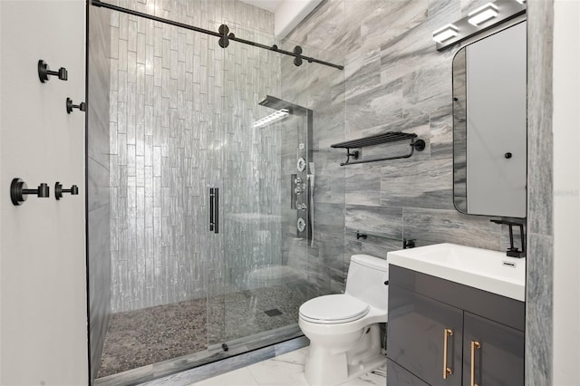 bathroom with a shower with door, vanity, tile walls, and toilet