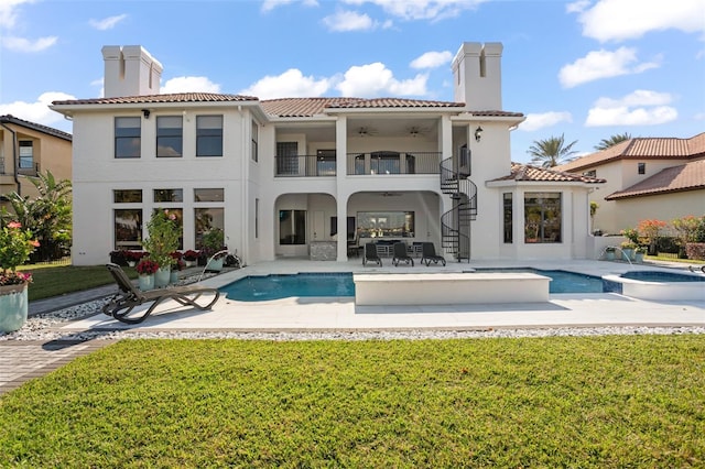 rear view of house with a pool with hot tub, a patio area, a balcony, and a lawn