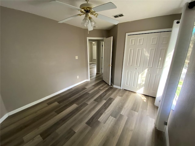 unfurnished bedroom featuring dark hardwood / wood-style flooring, ceiling fan, and a closet