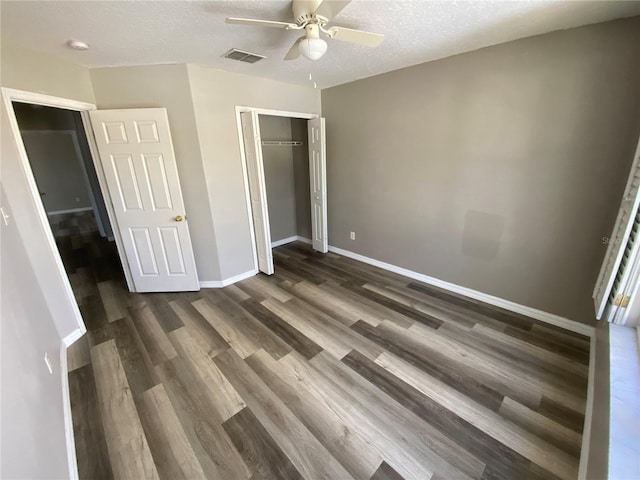 unfurnished bedroom with ceiling fan, dark wood-type flooring, a textured ceiling, and a closet