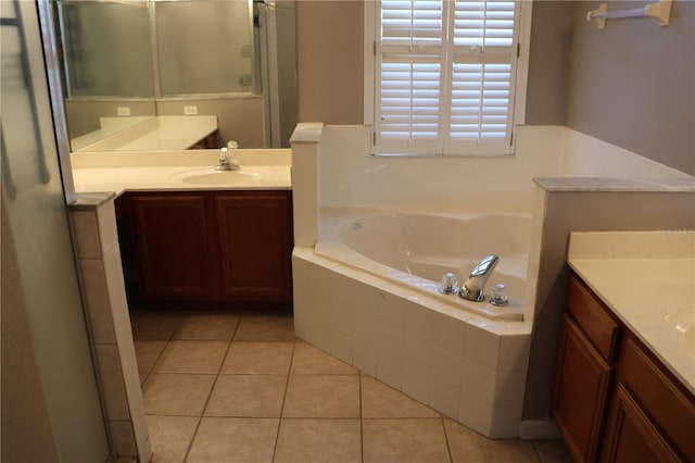 bathroom with tile patterned floors, vanity, and a relaxing tiled tub