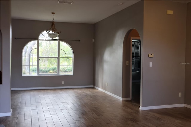 unfurnished room featuring wood-type flooring and an inviting chandelier