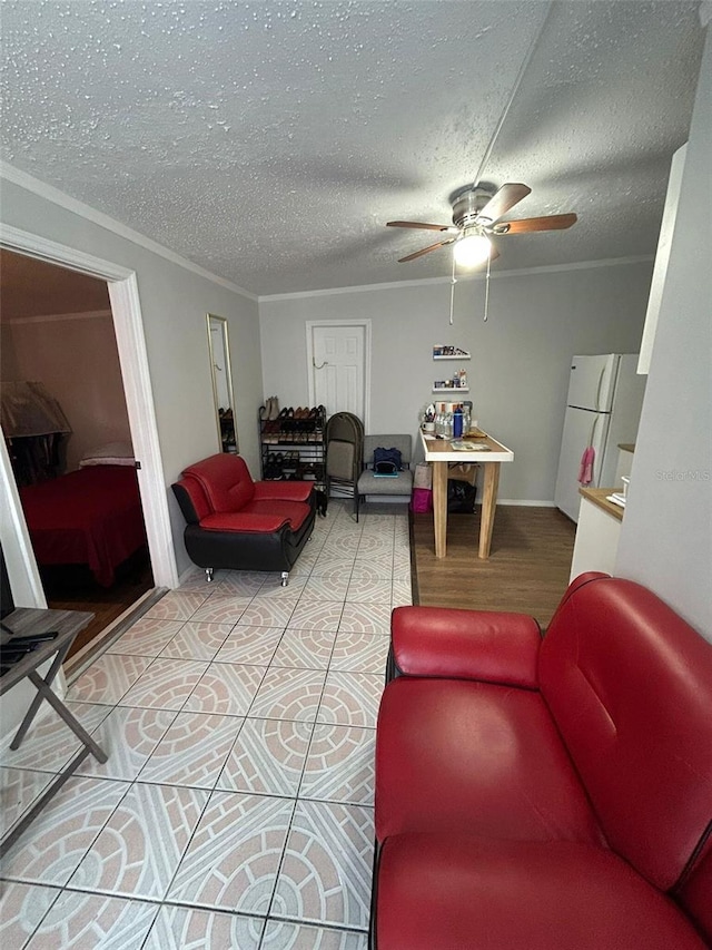 living room featuring ceiling fan, wood-type flooring, ornamental molding, and a textured ceiling