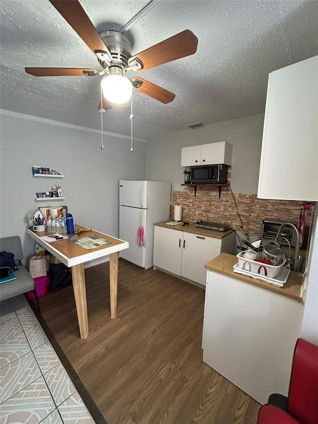 kitchen featuring backsplash, white cabinets, hardwood / wood-style flooring, ceiling fan, and white fridge