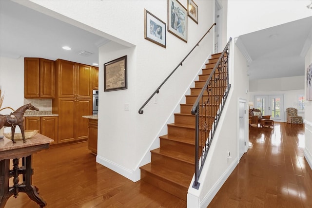 stairway with french doors and hardwood / wood-style flooring