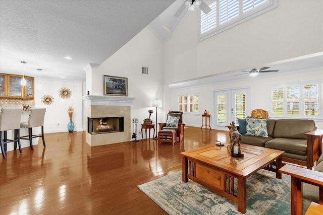 living room with ceiling fan, plenty of natural light, a high ceiling, and hardwood / wood-style flooring