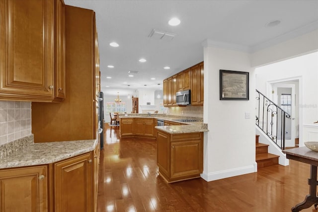 kitchen featuring kitchen peninsula, appliances with stainless steel finishes, backsplash, light stone countertops, and dark hardwood / wood-style floors