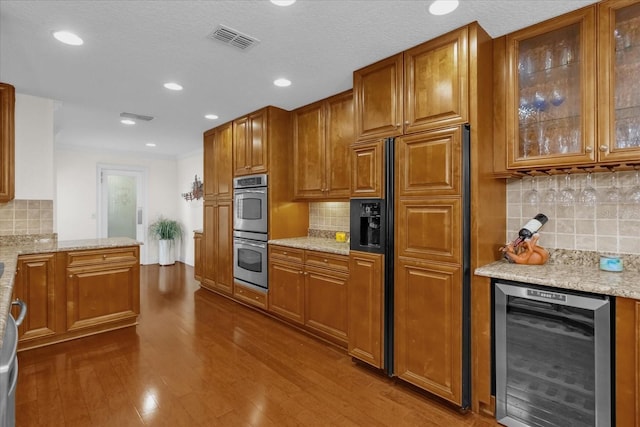 kitchen with light stone countertops, stainless steel double oven, tasteful backsplash, wine cooler, and paneled built in refrigerator