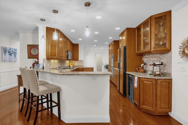 kitchen featuring light stone countertops, hanging light fixtures, kitchen peninsula, crown molding, and decorative backsplash