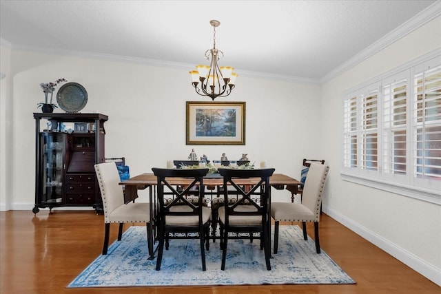 dining area with crown molding, wood-type flooring, and an inviting chandelier