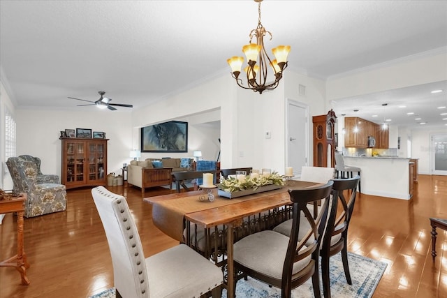 dining room with hardwood / wood-style floors, ceiling fan with notable chandelier, and ornamental molding