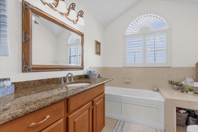 bathroom with tile patterned flooring, a washtub, vanity, and vaulted ceiling