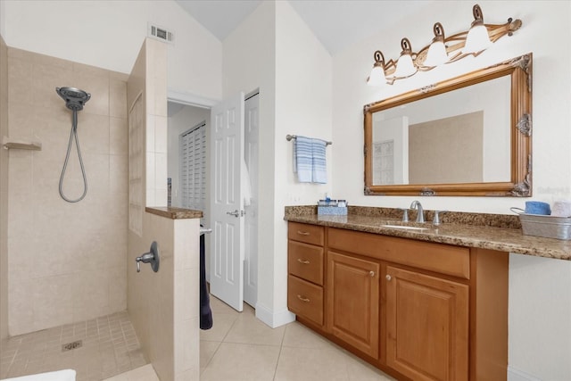 bathroom featuring tile patterned flooring, vanity, lofted ceiling, and tiled shower