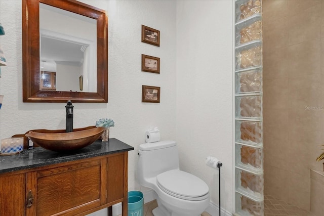 bathroom with vanity, toilet, and tiled shower