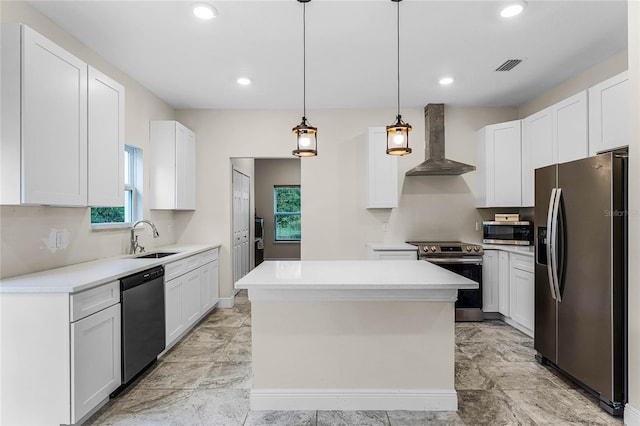 kitchen featuring wall chimney exhaust hood, a center island, white cabinetry, and appliances with stainless steel finishes