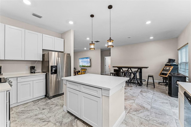 kitchen with white cabinets, stainless steel fridge, a kitchen island, and hanging light fixtures