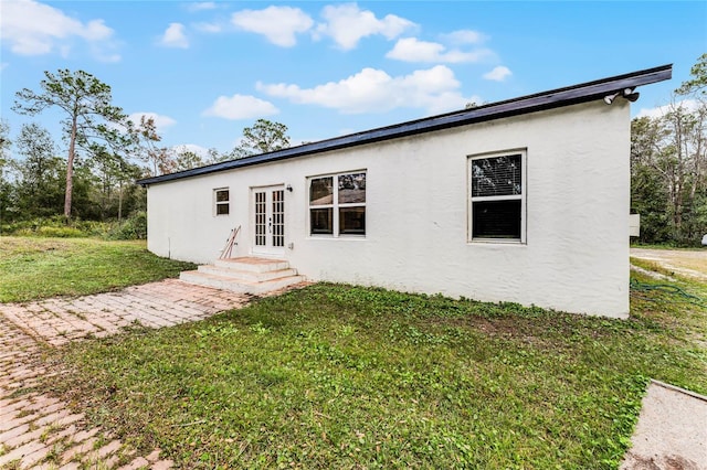 rear view of house with french doors and a lawn