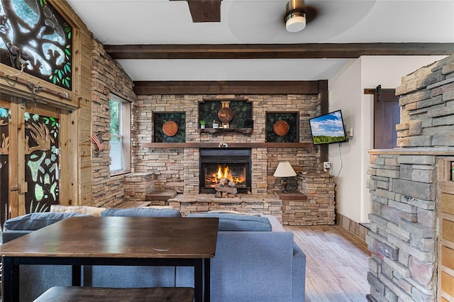 living room featuring beamed ceiling, ceiling fan, light wood-type flooring, and a fireplace