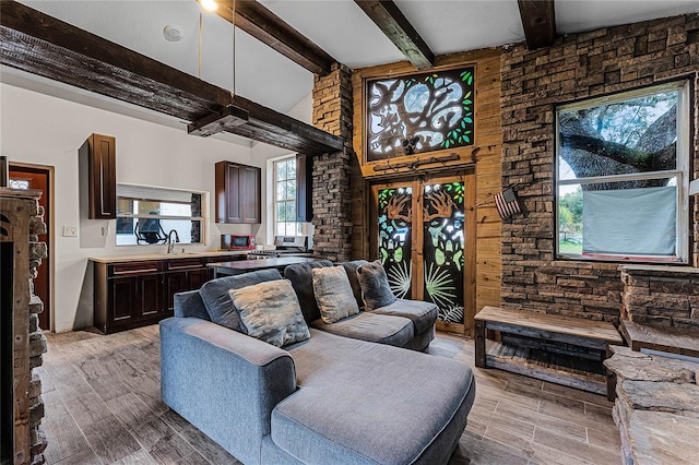 living room featuring beam ceiling, a fireplace, and sink