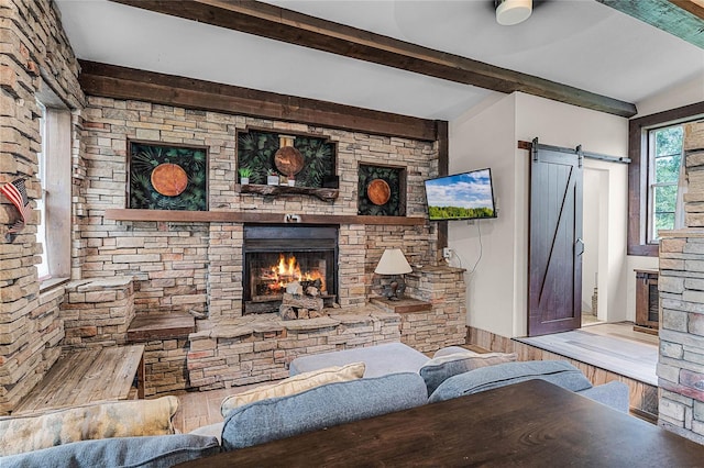 living room with a barn door, light hardwood / wood-style flooring, and a stone fireplace