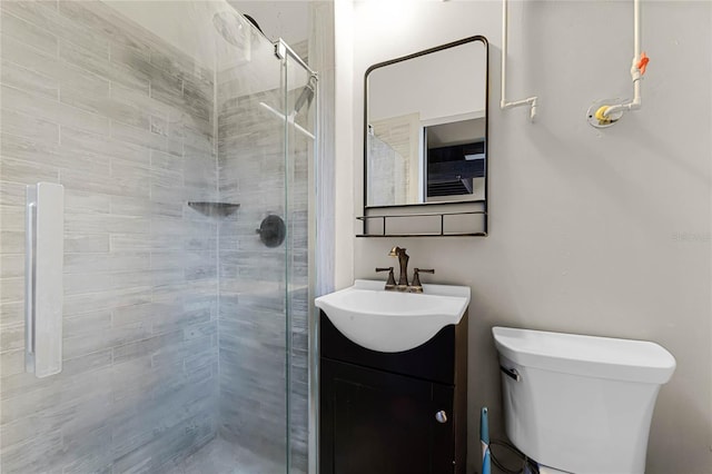 bathroom featuring vanity, a shower with shower door, and toilet