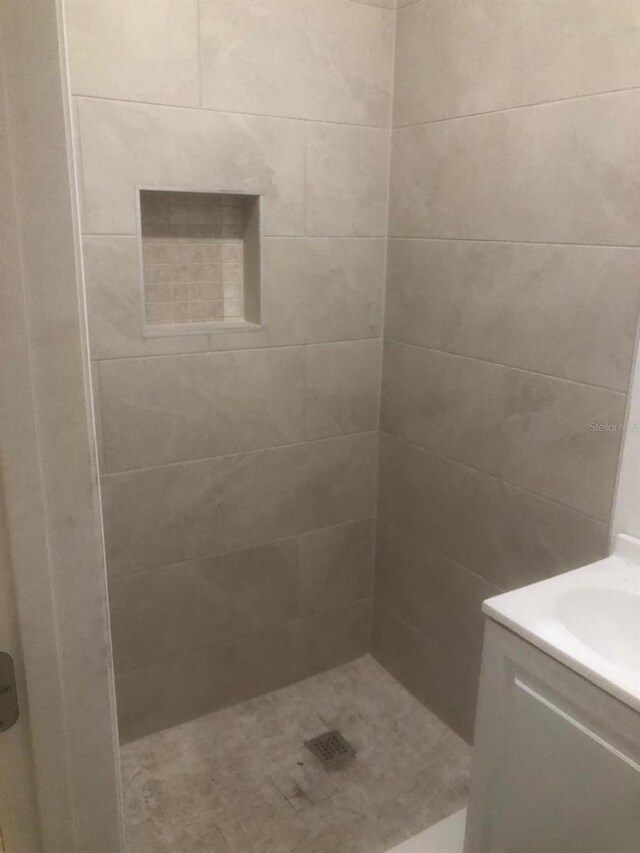 bathroom with tiled shower and vanity