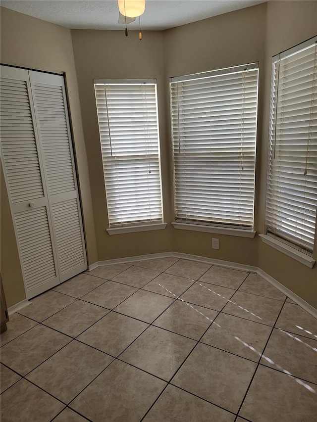 unfurnished dining area with ceiling fan and light tile patterned flooring