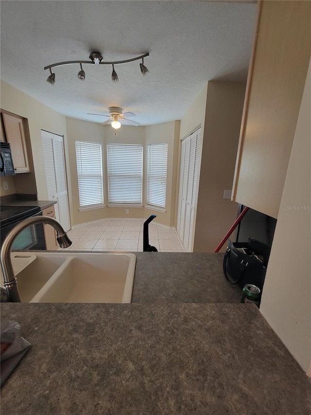 kitchen featuring ceiling fan, sink, rail lighting, and a textured ceiling