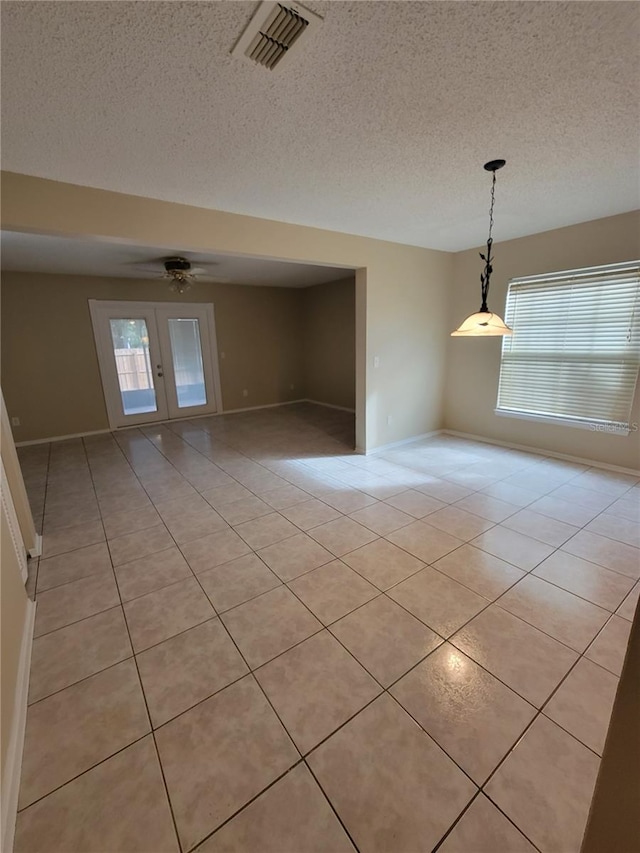 tiled spare room featuring ceiling fan, french doors, and a textured ceiling