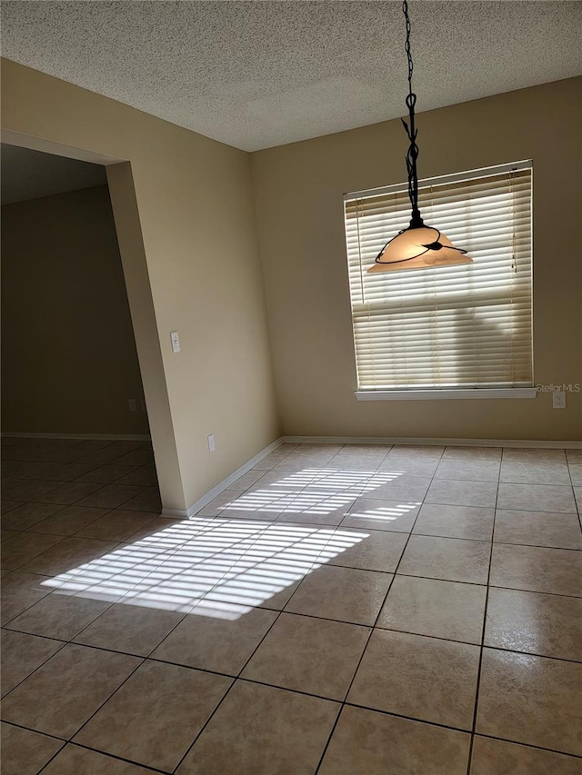 unfurnished dining area featuring light tile patterned floors, a healthy amount of sunlight, and a textured ceiling