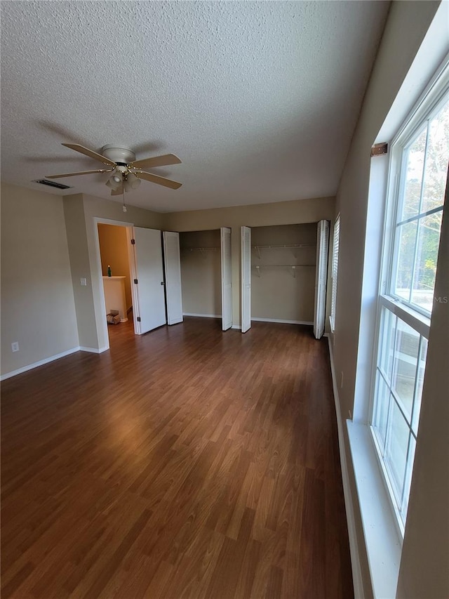 interior space with a textured ceiling, dark hardwood / wood-style floors, and ceiling fan