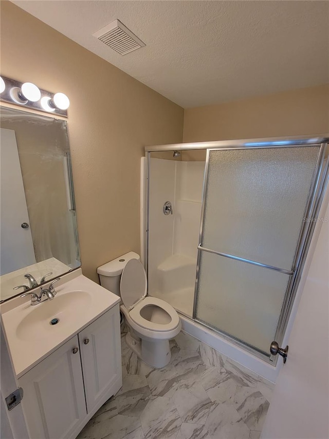 bathroom with a shower with door, vanity, a textured ceiling, and toilet