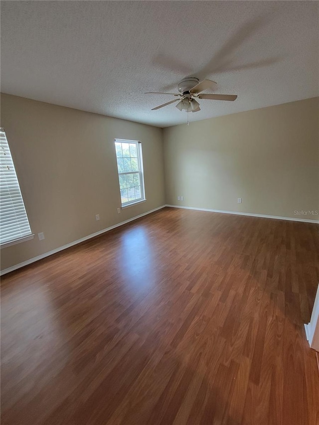 empty room with ceiling fan, wood-type flooring, and a textured ceiling